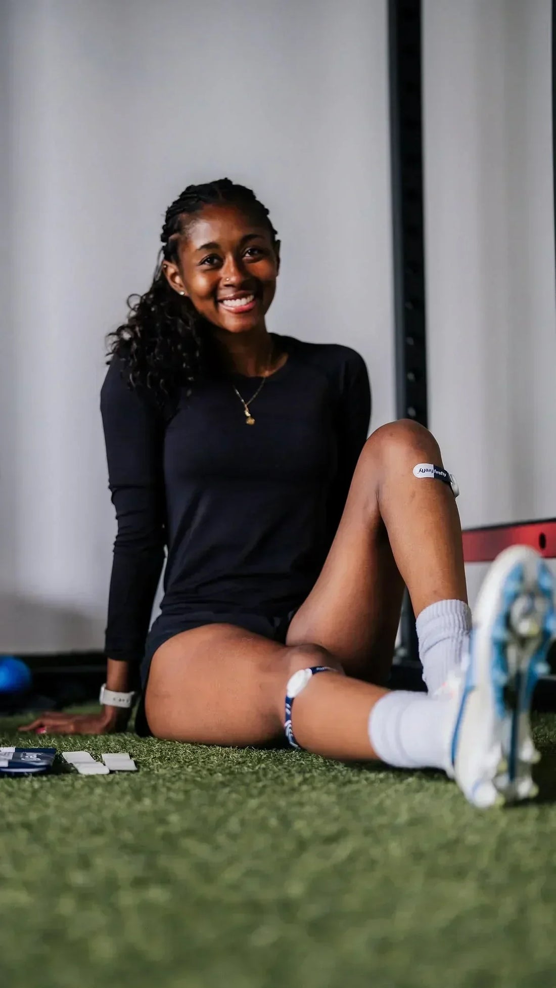 Athlete relaxing after exercise while wearing Firefly recovery devices on both lower legs to support post-workout recovery.