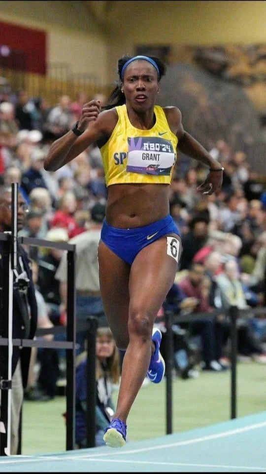 Elite runner sprinting during an indoor track race, demonstrating powerful stride, speed, and efficient running form.